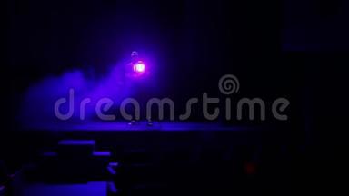 一个照明者用烟雾引导一束光线从舞台上的聚光灯照射到体育馆